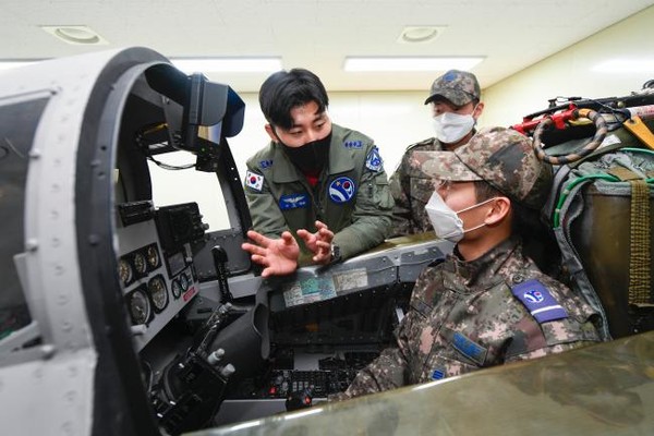 공군제10전투비행단의 ‘비행단 항공작전 임무 현장 견학’에 참여한 한 병사(오른쪽)가 모의비행훈련(CPT) 장비 탑승 체험을 하고 있다.(사진=공군제10전투비행단 제공)