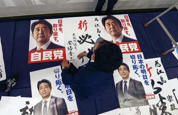 일본 참의원 선거 투표일인 지난 10일 일본 야마구치현 야마구치시에 있는 에지마 기요시 자민당 후보의 진영에서 관계자가 작업 중인 가운데 아베 신조 전 일본 총리의 사진이 담긴 자민당 홍보물이 놓여 있다.(사진=교도 연합뉴스)